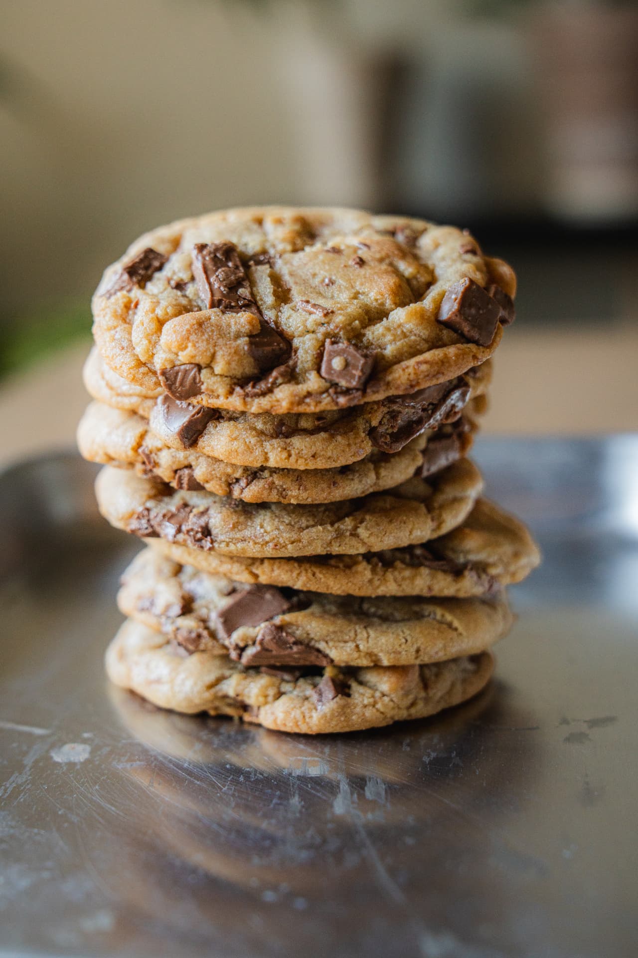 A tall stack of thick chocolate chip cookies on a metal tray